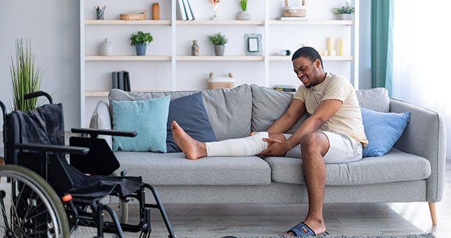 Hombre en sofá con pierna rota
